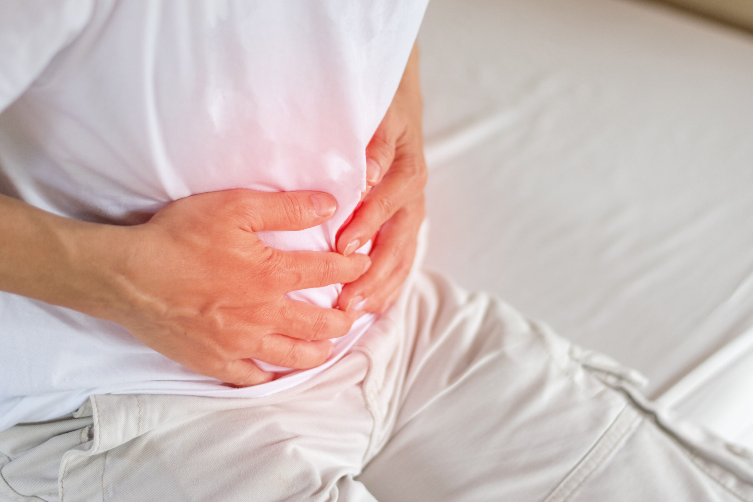 Person holding their upper abdomen in discomfort
