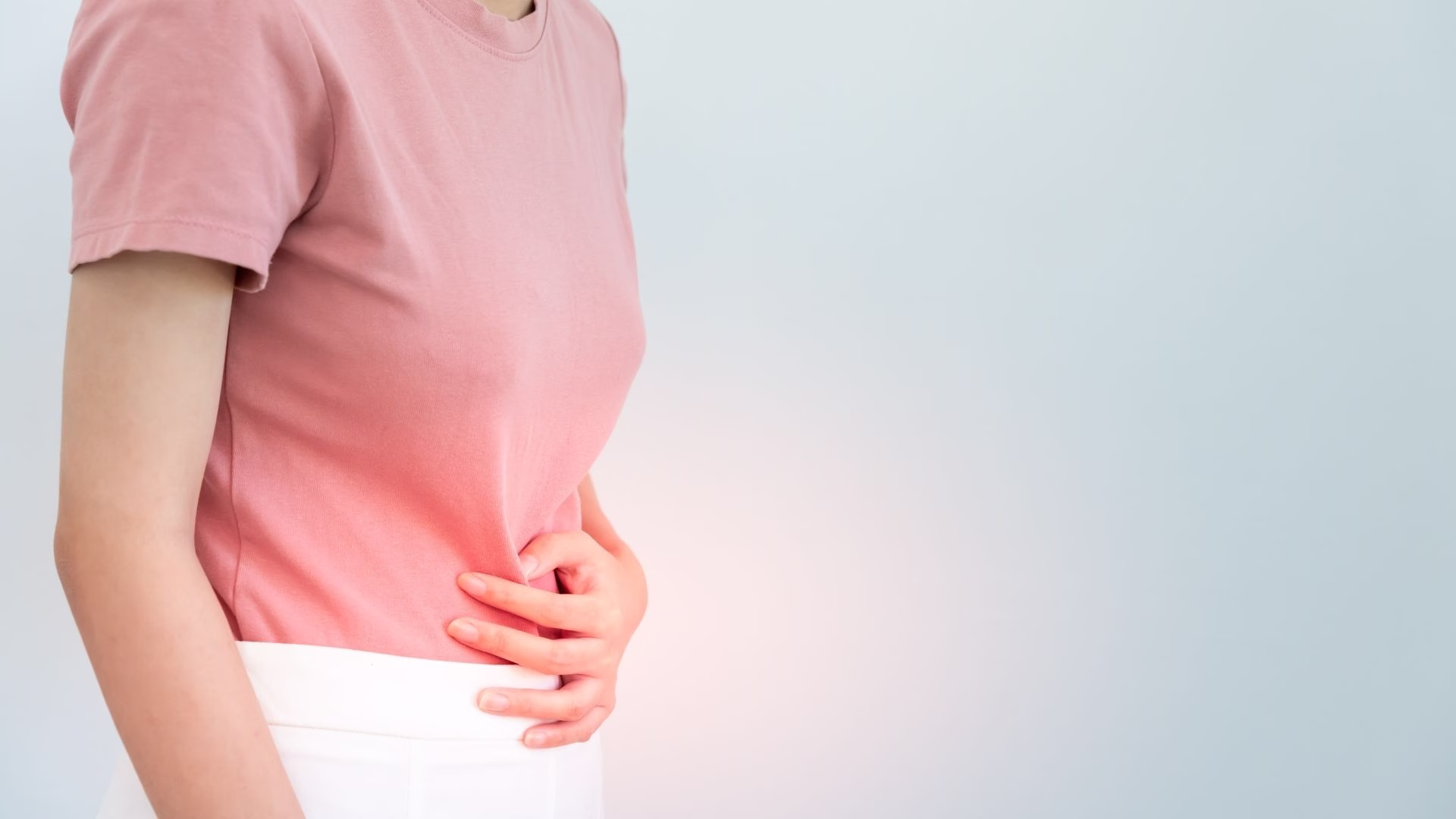 Adult holding the abdomen near the navel, where an umbilical hernia can cause discomfort